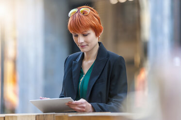 Junge Frau benutzt digitales Tablet in einem Café im Freien - DIGF000409