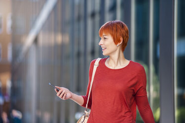 Lächelnde junge Frau mit Mobiltelefon in der Hand - DIGF000429