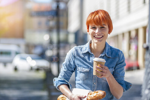 Porträt einer lächelnden jungen Frau mit Kaffee und Baguette - DIGF000442