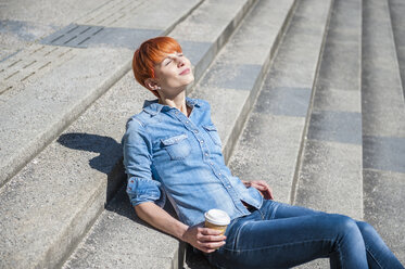 Junge Frau entspannt sich auf einer Treppe mit Kaffee zum Mitnehmen - DIGF000445