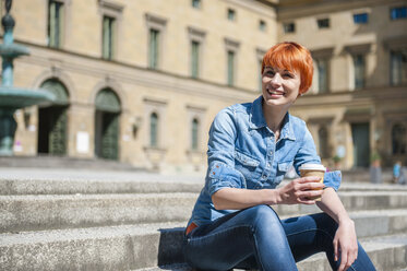 Junge Frau entspannt sich auf einer Treppe mit Kaffee zum Mitnehmen - DIGF000446