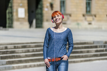 Smiling young woman listening to music outdoors - DIGF000452