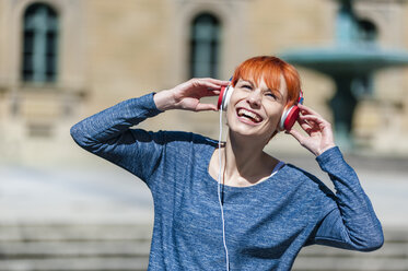 Happy young woman listening to music outdoors - DIGF000453