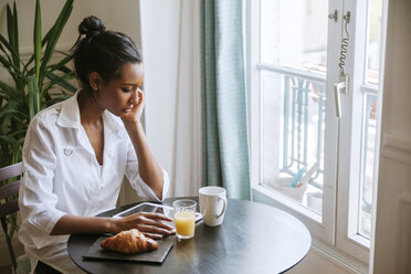 Young woman using digital tablet at breakfast table - ZEDF000101