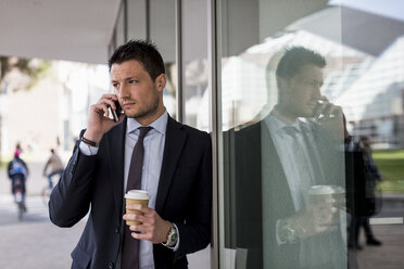 Businessman outdoors with cell phone and coffee to go - MAUF000508