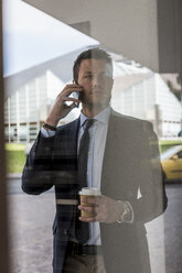 Businessman outdoors with cell phone and coffee to go - MAUF000511