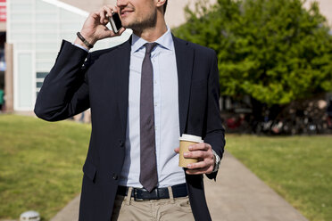 Businessman outdoors with cell phone and coffee to go - MAUF000516