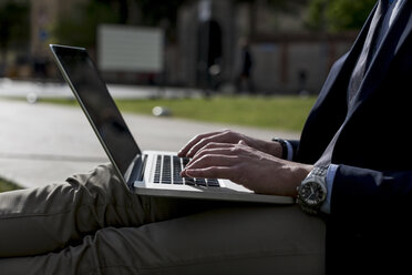 Businessman using laptop outdoors - MAUF000519