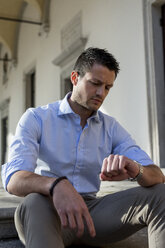 Man sitting outdoors checking the time - MAUF000538