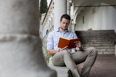 Mann sitzt im Freien und liest ein Buch - MAUF000541