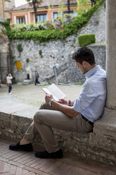 Mann sitzt im Freien und liest ein Buch - MAUF000542