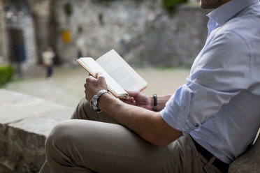 Mann sitzt im Freien und liest ein Buch - MAUF000543