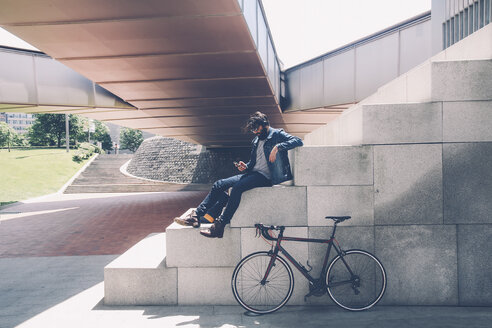 Spain, Bilbao, Man with smartphone and headphone, racing cycle - RTBF000184