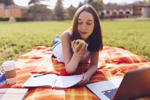 Student im Park, der einen Apfel isst, lizenzfreies Stockfoto