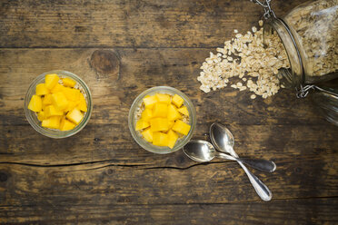 Zwei Gläser Overnight Oats mit gewürfelter Mango auf Holz - LVF004852