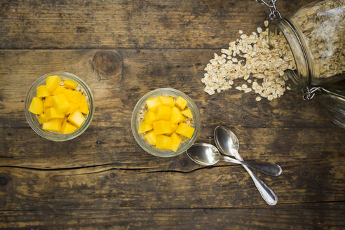 Zwei Gläser Overnight Oats mit gewürfelter Mango auf Holz - LVF004852