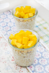 Zwei Gläser Overnight Oats mit gewürfelter Mango auf dem Tablett - LVF004854