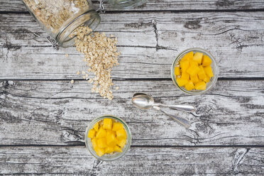 Two glasses of overnight oats with diced mango on wood - LVF004856