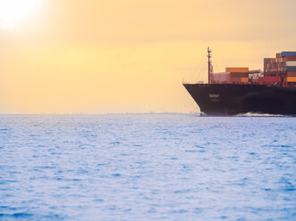 Germany, near Cuxhaven, North Sea, container ship at sunset - KRPF001744