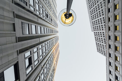 Germany, Berlin, lighted street lamp between two skyscrapers seen from below - ZMF000467