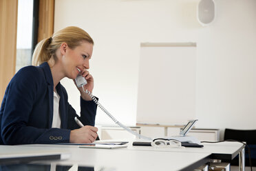 Lächelnde Geschäftsfrau am Bürotisch am Telefon - CHAF001671