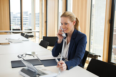 Lächelnde Geschäftsfrau am Bürotisch am Telefon - CHAF001674