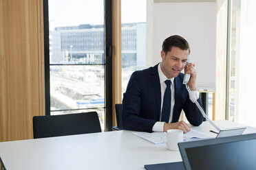 Businessman at office desk on the phone - CHAF001696