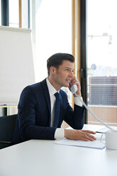 Businessman at office desk on the phone - CHAF001697