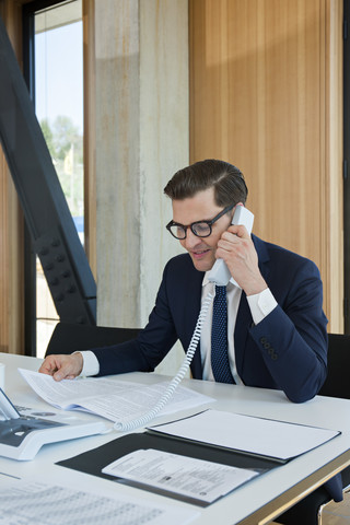 Geschäftsmann am Bürotisch beim Telefonieren, lizenzfreies Stockfoto