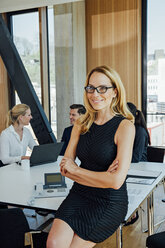 Portrait of smiling businesswoman with colleagues in background - CHAF001703