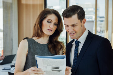 Businessman and woman discussing booklet in office - CHAF001714