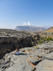 Oman, Jebel Shams, Frau auf Aussichtspunkt sitzend - AMF004883