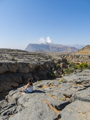 Oman, Jebel Shams, woman sitting on viewing point - AMF004883