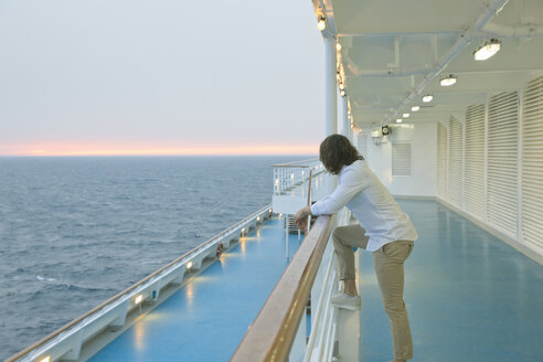 Junger Mann steht an Deck eines Schiffes und beobachtet den Sonnenuntergang - SEF000910