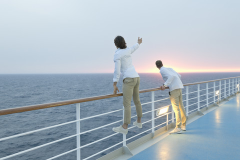 Junge Männer stehen an Deck eines Schiffes und beobachten den Sonnenuntergang, lizenzfreies Stockfoto