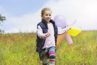 Young girl running with balloons over meadow - MAEF011616