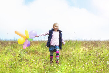 Junges Mädchen läuft mit Luftballons über eine Wiese - MAEF011617