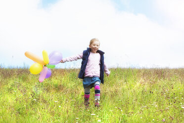 Young girl running with balloons over meadow - MAEF011617