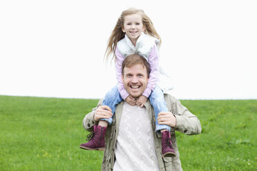 Glücklicher Vater trägt Tochter auf den Schultern auf einer Wiese - MAEF011623