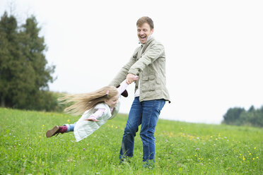 Happy father turning daughter in meadow - MAEF011624