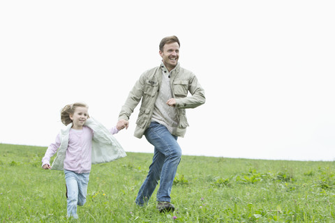 Happy father and daughter running in meadow stock photo