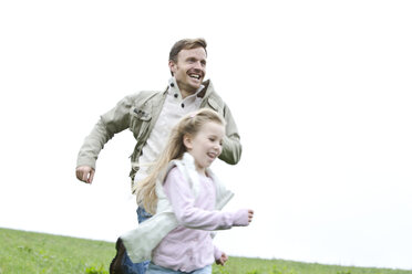 Glücklicher Vater und Tochter laufen auf einer Wiese - MAEF011628