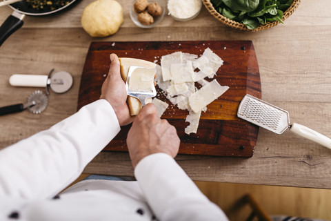 Koch bereitet Füllung für Ravioli vor, schneidet Parmesankäse, lizenzfreies Stockfoto