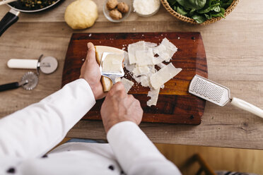 Koch bereitet Füllung für Ravioli vor, schneidet Parmesankäse - JRFF000646