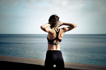 Rückenansicht einer Frau, die vor dem Meer trainiert - SIPF000441