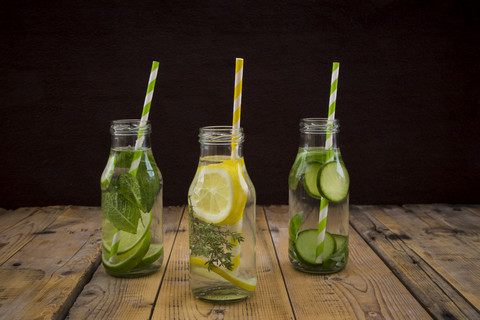 Drei Glasflaschen mit Tafelwasser, aromatisiert mit verschiedenen Früchten und Kräutern, lizenzfreies Stockfoto