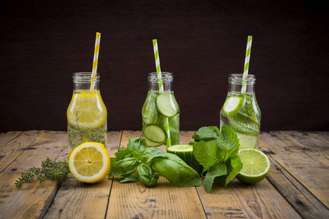 Drei Glasflaschen mit Tafelwasser, aromatisiert mit verschiedenen Früchten und Kräutern, lizenzfreies Stockfoto