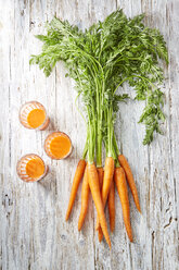 Carrots and three glasses of carrot juice on wood - KSWF001761