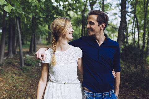 Verliebtes Paar geht Arm in Arm im Wald spazieren, lizenzfreies Stockfoto