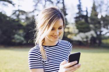 Porträt einer lächelnden blonden Frau, die auf ihr Smartphone schaut - GIOF000999